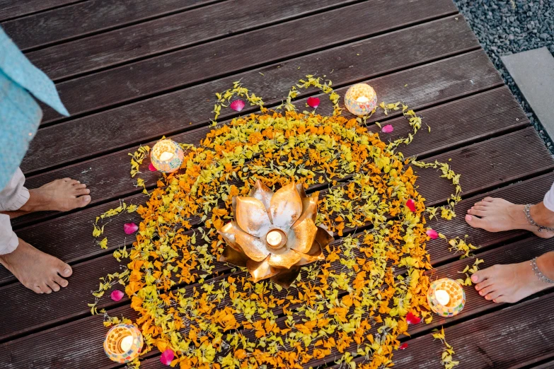 a group of people standing on top of a wooden floor, flower decorations, orange candle flames, ariel view, lotus