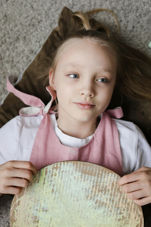 a little girl laying on the floor holding a basket, an album cover, inspired by Elsa Beskow, pexels contest winner, greta thunberg as gollum, fleshy creature above her mouth, pastel', wearing an apron