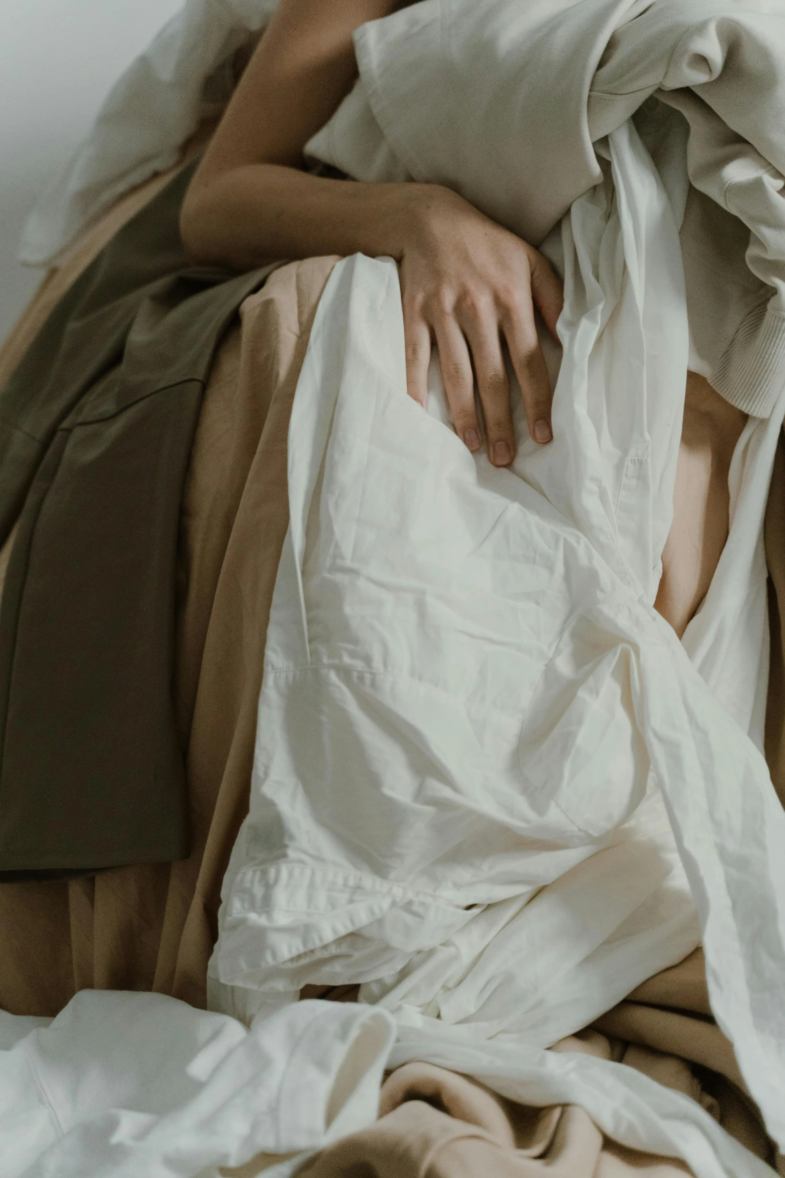 a woman laying on top of a bed covered in sheets, inspired by Jacques-Louis David, trending on unsplash, classical realism, long skirt, texture detail, white sleeves, beige colors