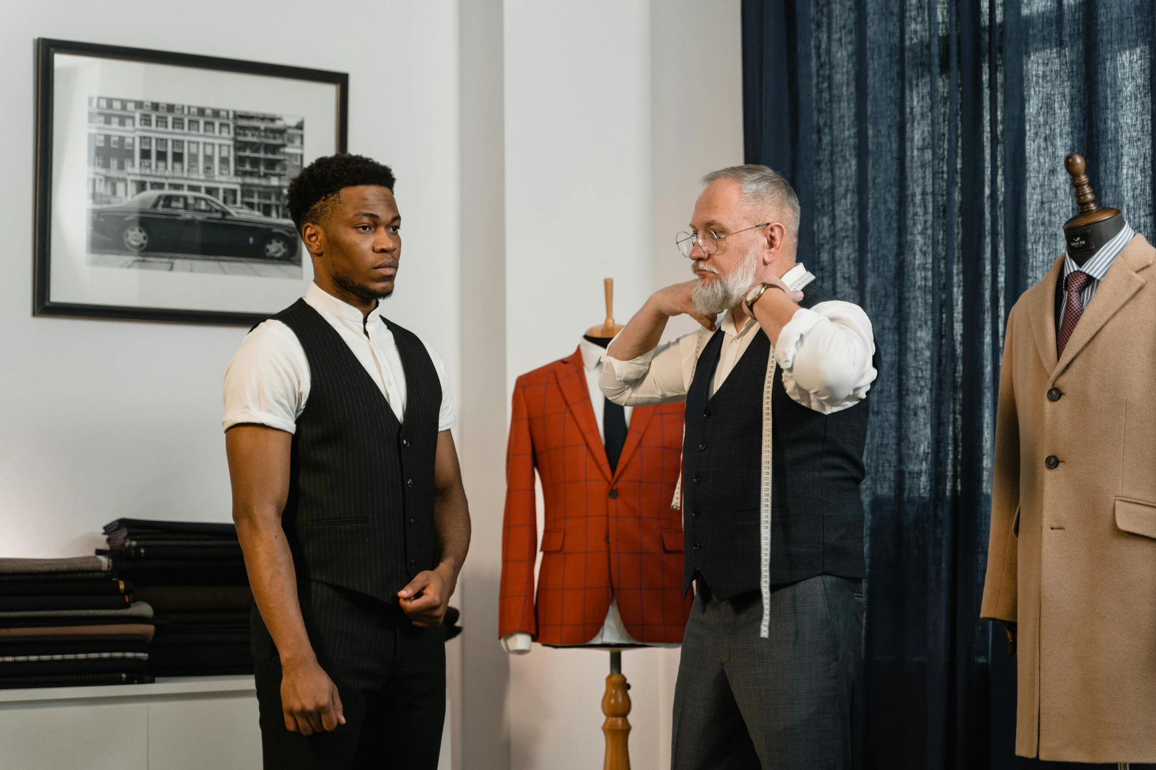 two men standing next to each other in a room, inspired by Frank Mason, pexels contest winner, wearing suit vest, put on a mannequin, two models in the frame, body fitted dart manipulation