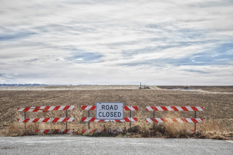 a road closed sign sitting on the side of a road, by Dan Frazier, unsplash, land art, background image, farmland, various posed, set photo