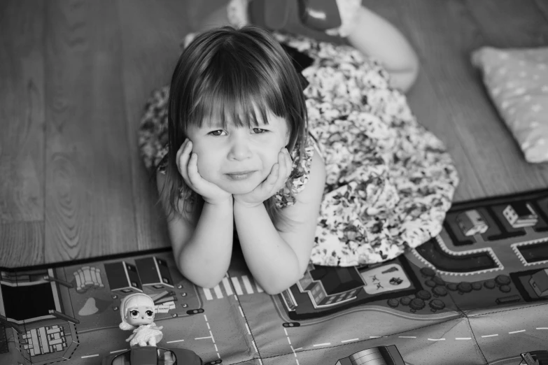 a black and white photo of a little girl laying on the floor, pixabay contest winner, annoyed expression, toy photo, cars portraits, 🤤 girl portrait