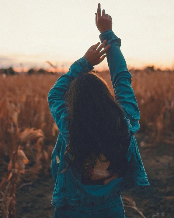 a woman standing in a field with her hands in the air, an album cover, inspired by Elsa Bleda, trending on unsplash, denim, profile image, corn, snapchat photo