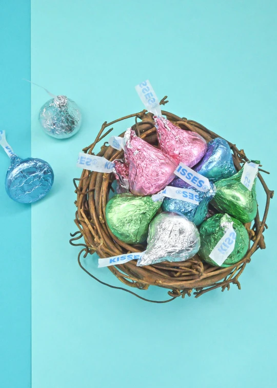 a basket filled with chocolate eggs on top of a blue table, tissue ornament, bliss, full product shot, joyous trumpets