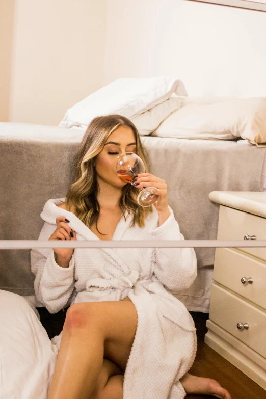 a woman in a bathrobe sitting on the floor, by Robbie Trevino, pexels contest winner, drinking cocktail, amber heard squatting on a bed, olivia culpo, sydney sweeney