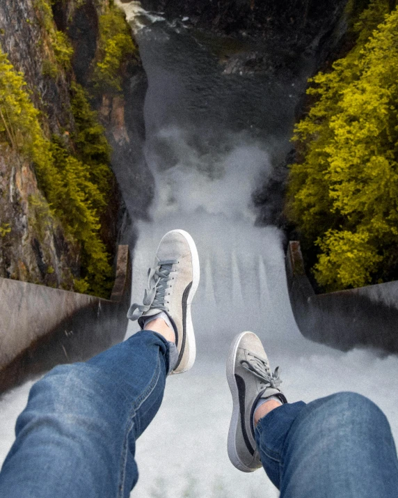 a person sitting on a ledge above a waterfall, pexels contest winner, wearing white sneakers, flying towards the camera, thumbnail, snapchat photo