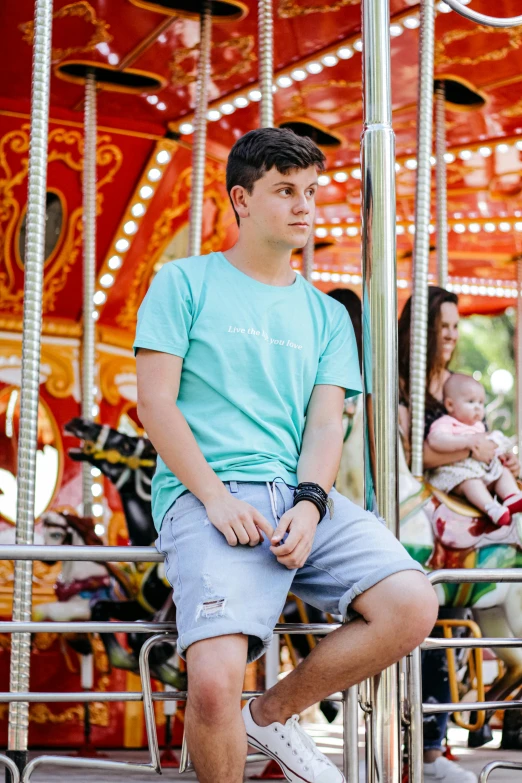 a young man sitting on top of a carousel, a portrait, pexels contest winner, wearing shorts and t shirt, turquoise, dreamworld, caspar david