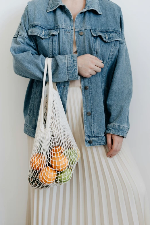 a woman in a denim jacket holding a bag of fruit, pexels contest winner, renaissance, coated pleats, nets, white hue, transparent
