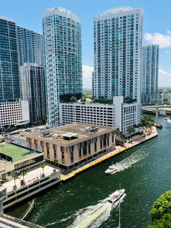 a boat traveling down a river next to tall buildings, miami, photograph from above, thumbnail, white marble buildings