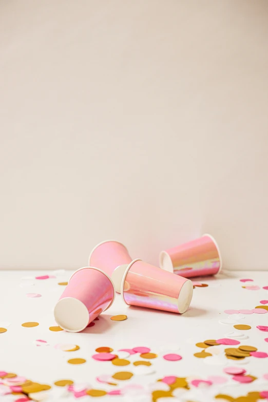 two pink cups sitting on top of a table covered in confetti, happening, petal pink gradient scheme, foil, detailed product shot, on high-quality paper