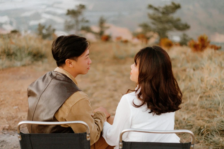 a man and a woman sitting in lawn chairs, pexels contest winner, romanticism, asian man, on a hill, facing each other, brown