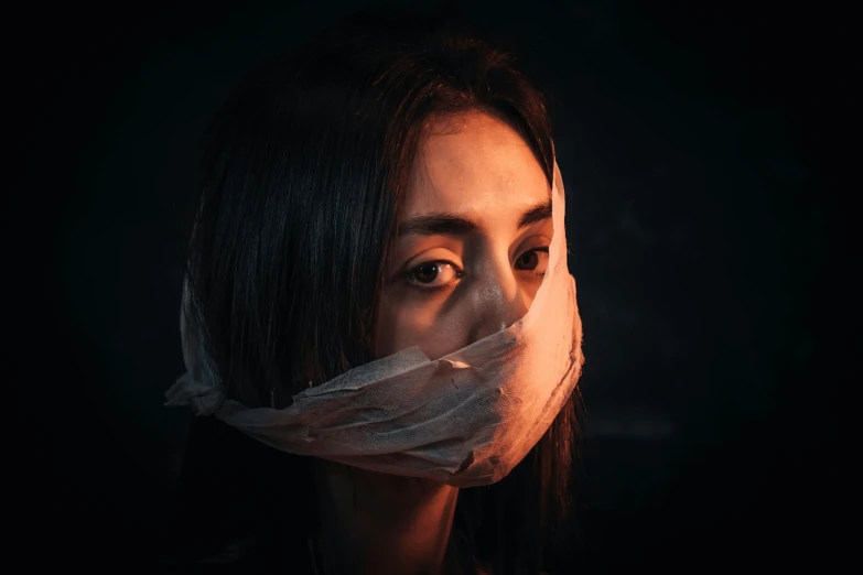 a woman with a piece of plastic covering her face, pexels contest winner, antipodeans, covered in bandages, a young asian woman, serious expression, dark backround
