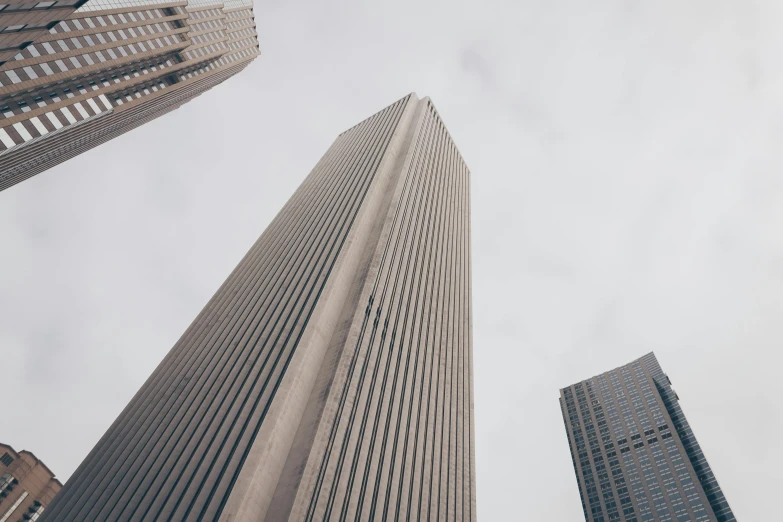 a group of tall buildings sitting next to each other, an album cover, pexels contest winner, brutalism, gray skies, high angle vertical, sins inc skyscraper front, extremely high resolution