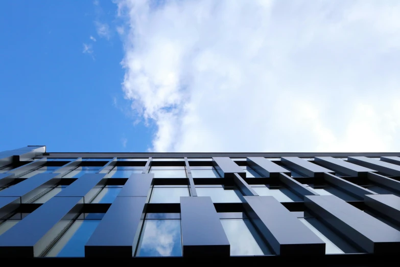 a tall building with a blue sky in the background, a screenshot, inspired by Tadao Ando, unsplash, black windows, iron cladding, looking upwards, thumbnail