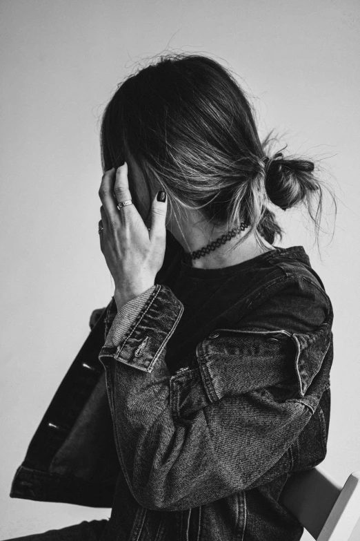 a black and white photo of a woman covering her face, trending on pexels, aestheticism, wearing a jeans jackets, messy bun, wearing choker, heartbroken