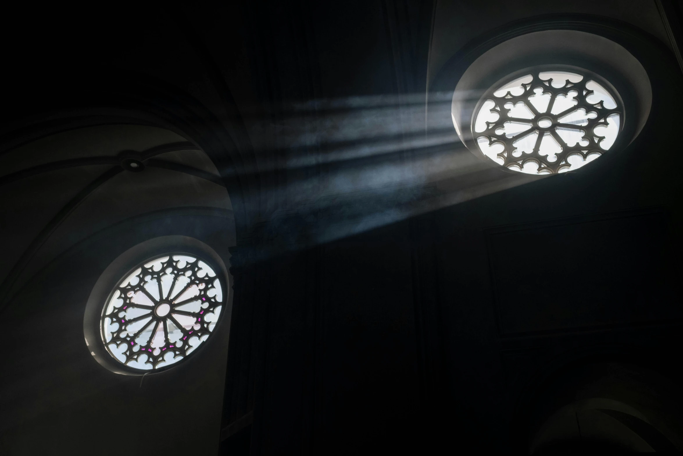 two round stained glass windows in a dark room, light and space, smoke fog and crepuscular rays, looking up, cathedrals, lit from above