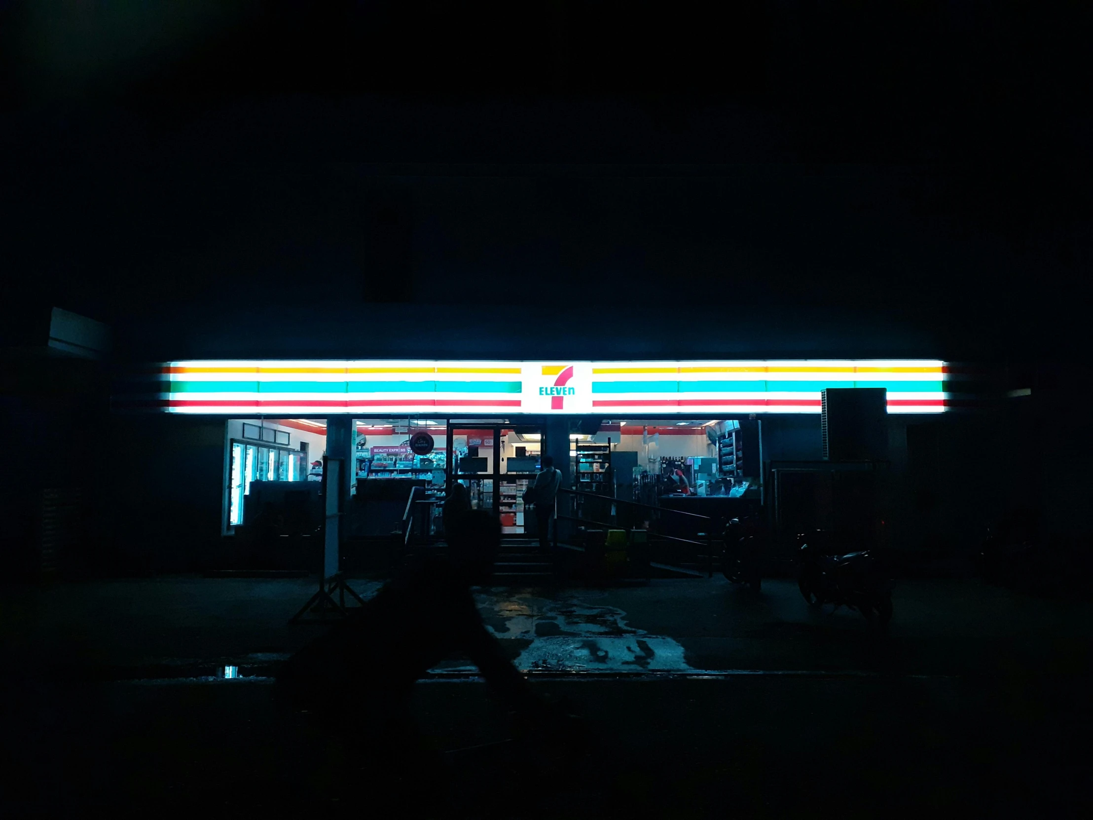 a person sitting on a bench in front of a gas station, an album cover, inspired by Elsa Bleda, unsplash, midnight zone, pepsi, shop front, todd hido