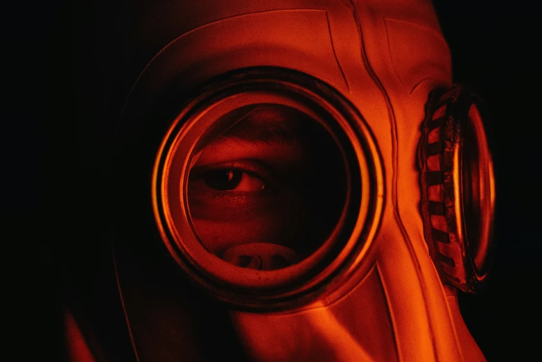 a close up of a person wearing a gas mask, nuclear art, his eyes glowing red, looking in a mirror, movie filmstill, agent orange