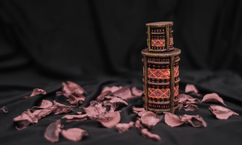 a vase sitting on top of a black cloth, by Emma Andijewska, pexels contest winner, cloisonnism, black and reddish color armor, perfume, the flower tower, pyrography