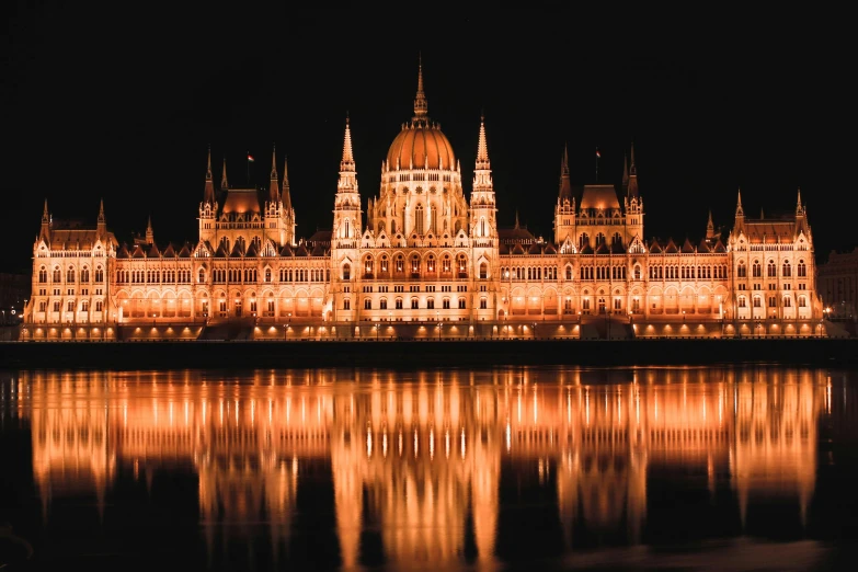 a large building lit up at night next to a body of water, by Matija Jama, pexels contest winner, baroque, parliament, gigapixel photo, thumbnail, brown