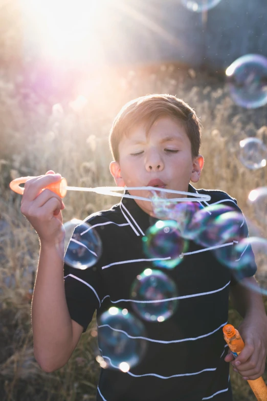 a young boy blowing bubbles in a field, a picture, pexels contest winner, light stubble, professionally color graded, resin, albuquerque