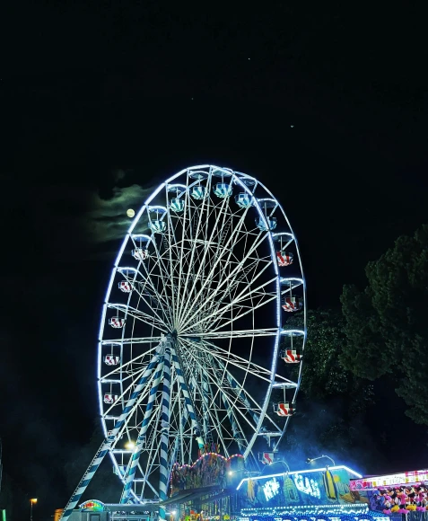 a large ferris wheel sitting in the middle of a park, by Niko Henrichon, pexels contest winner, high blue lights, eyelevel!!! view!!! photography, moonlight grey, summer festival night