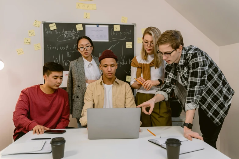 a group of people standing around a table with a laptop, trending on pexels, classroom, ash thorp khyzyl saleem, thumbnail