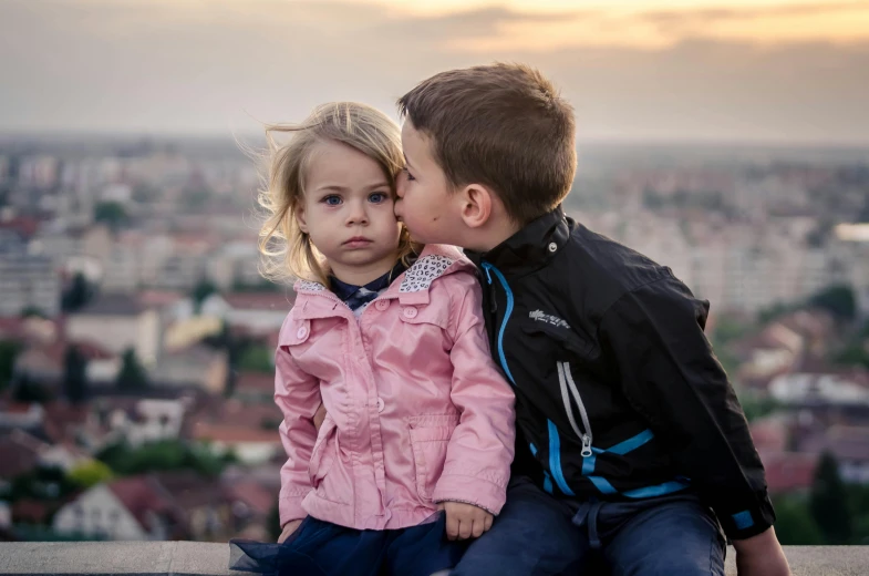 a couple of kids that are sitting on a ledge, by Joze Ciuha, pexels contest winner, realism, french kiss, 15081959 21121991 01012000 4k, arm around her neck, bosnian