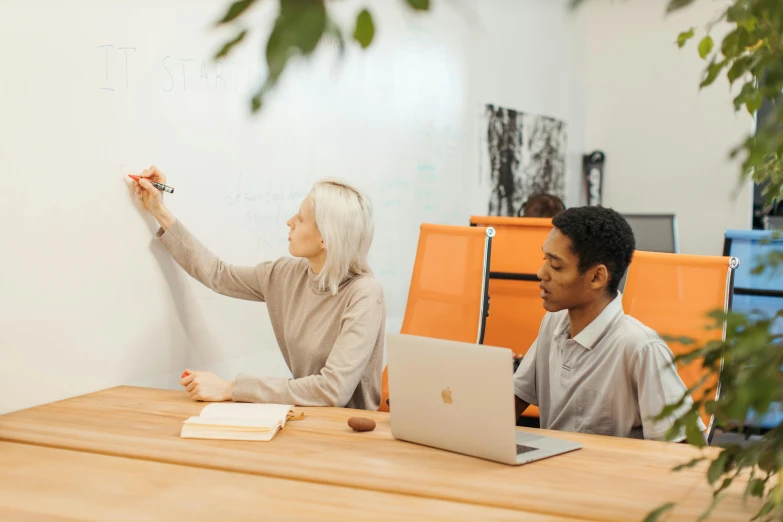 a man and woman sitting at a table writing on a whiteboard, by Adam Marczyński, pexels contest winner, creative coding, background image, leaked image