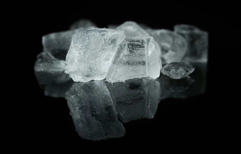 a pile of ice sitting on top of a table, by Adam Marczyński, pexels, on black background, milk cubes, cold hue's, clear reflection