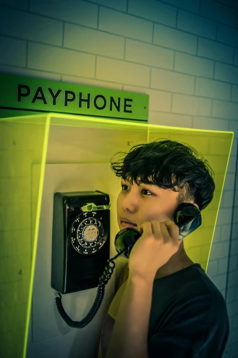 a man standing in front of a pay phone, a colorized photo, inspired by Nan Goldin, trending on pexels, headphones on head, ((yellow magic orchestra)), raytracing on, paul kwon