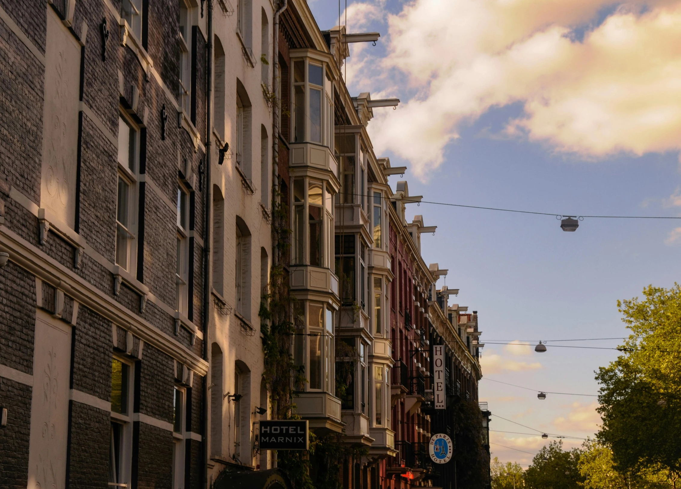 a city street filled with lots of tall buildings, by Jan Tengnagel, pexels contest winner, neoclassicism, view of houses in amsterdam, late afternoon light, wires hanging above street, brown