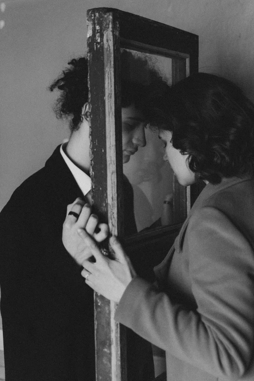 a woman adjusting a man's tie in front of a mirror, inspired by Sergio Larraín, behind bars, the cure, ffffound, peasant boy and girl first kiss