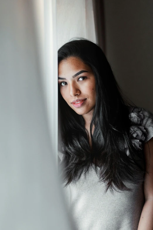 a woman standing in front of a window, with long black hair, flawless olive skin, riyahd cassiem, ( low key light )