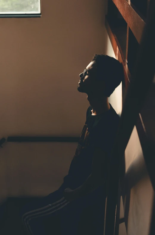 a person sitting on a chair in front of a window, pexels contest winner, dark skinned, silhouette of man, thoughtful pose, standing in a church