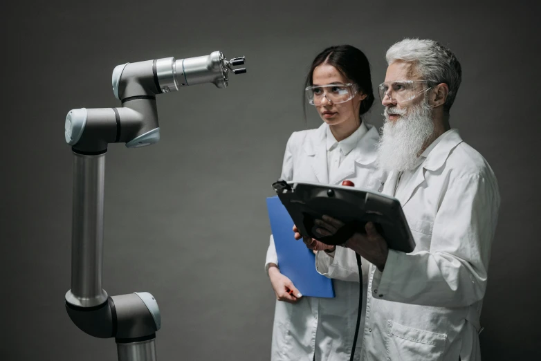 a couple of people standing next to each other, by Adam Marczyński, shutterstock, holography, industrial robot, old man, instagram post, on a advanced lab