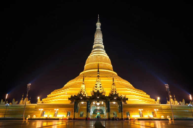 a large yellow pagoda lit up at night, square, touring, myanmar, fan favorite