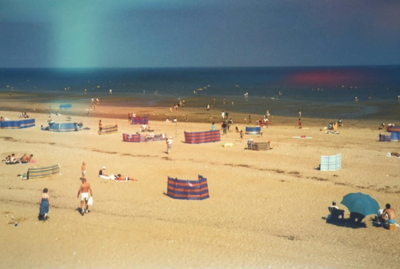 a group of people sitting on top of a sandy beach, a colorized photo, unsplash, plasticien, databending, northern france, medium format. soft light, beach aesthetic