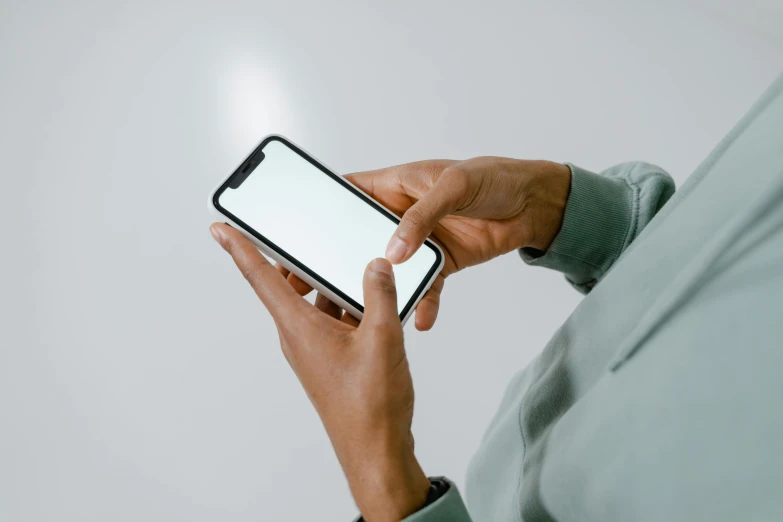 a woman holding a smart phone with a blank screen, by Carey Morris, trending on pexels, light and space, pale green glow, man is with black skin, on grey background, iphone 13