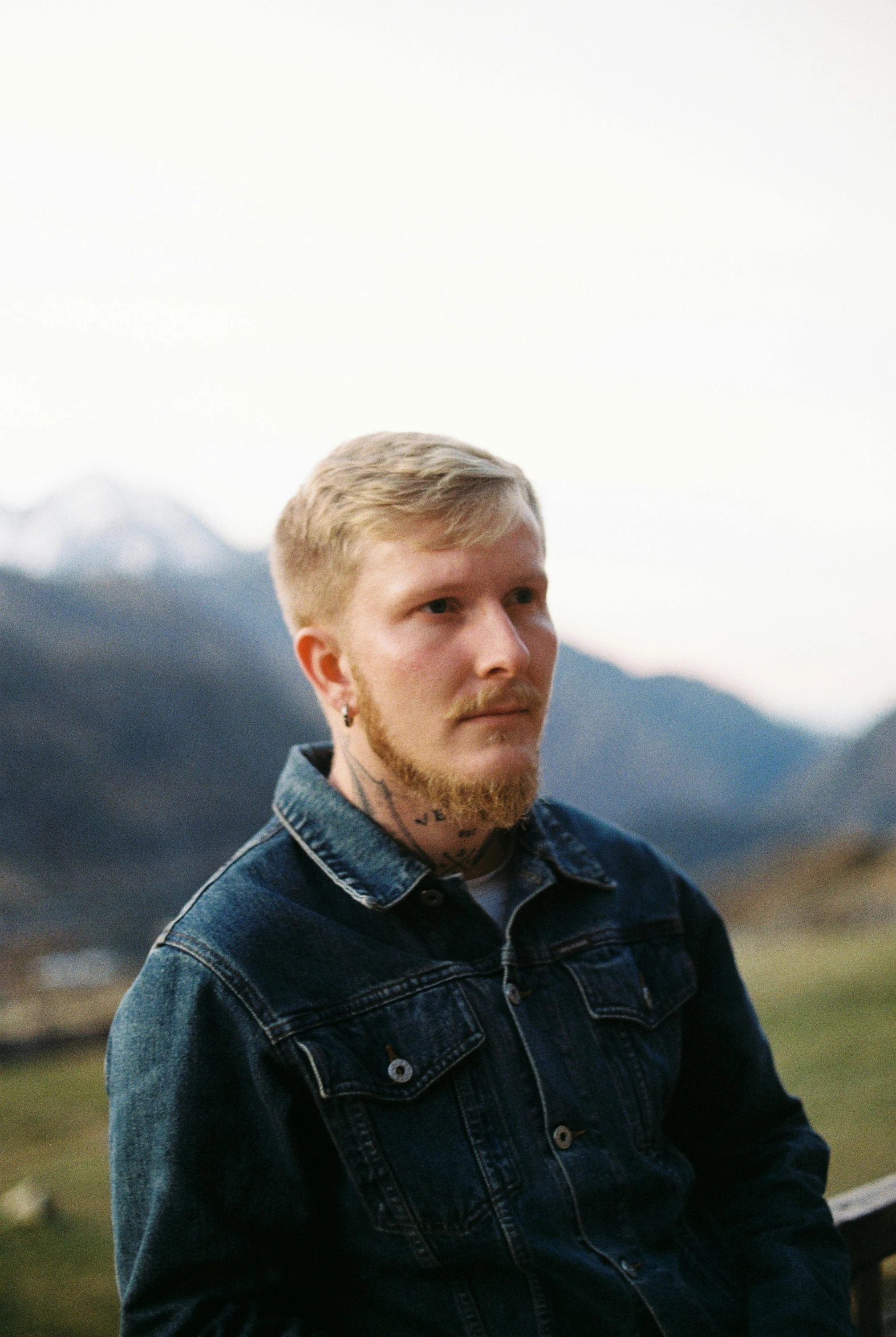 a man with a beard wearing a denim jacket, an album cover, inspired by Ásgrímur Jónsson, pexels contest winner, realism, mountainous setting, androgynous person, inked, headshot profile picture