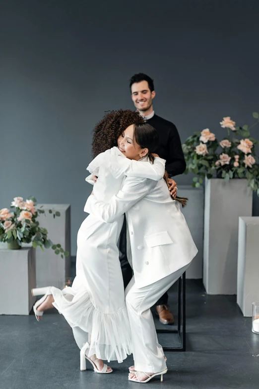 a couple of people that are hugging each other, wearing white suit, award - winning design, rituals, bouquets