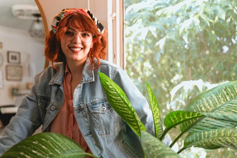 a woman sitting next to a potted plant, justina blakeney, a redheaded young woman, wearing a jeans jackets, avatar image