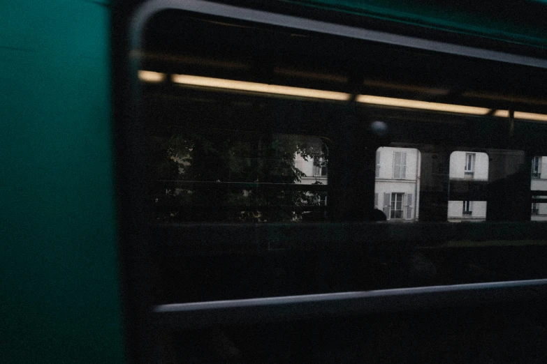 a close up of a train window with a building in the background, a picture, by Raphaël Collin, unsplash, realism, dark green tint, inside of a metro train, low quality footage, multiple stories