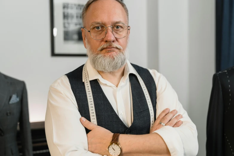 a man that is standing with his arms crossed, by László Balogh, unsplash, art nouveau, silver full beard, wearing a suit and glasses, professional picture, renzo piano