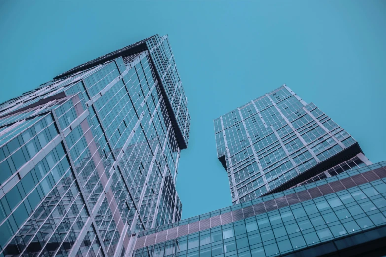 a couple of tall buildings sitting next to each other, a screenshot, by Adam Marczyński, pexels contest winner, light blue clear sky, glass ceilings, cyan, thumbnail