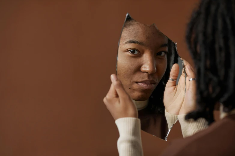 a woman looking at her reflection in a mirror, trending on pexels, hyperrealism, with brown skin, broken mirrors composition, wearing a brown, 1 4 9 3