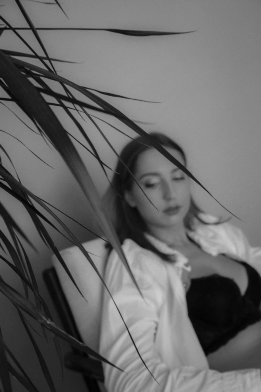 a woman sitting in a chair next to a plant, a black and white photo, aestheticism, 🤤 girl portrait, wearing white silk, devon cady-lee, sleepy