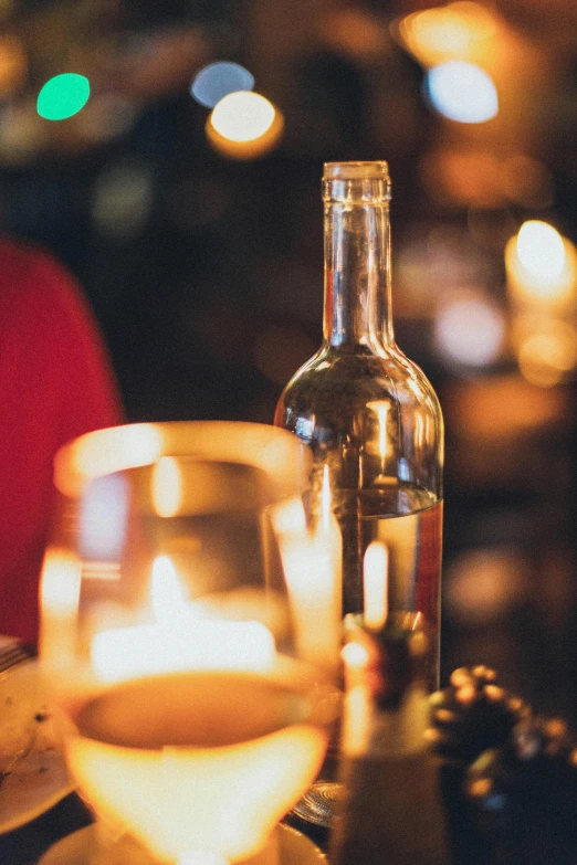 a glass of wine and a bottle of wine on a table, by Daniel Lieske, pexels, renaissance, cozy candlelight, looking left, holiday vibe, low details