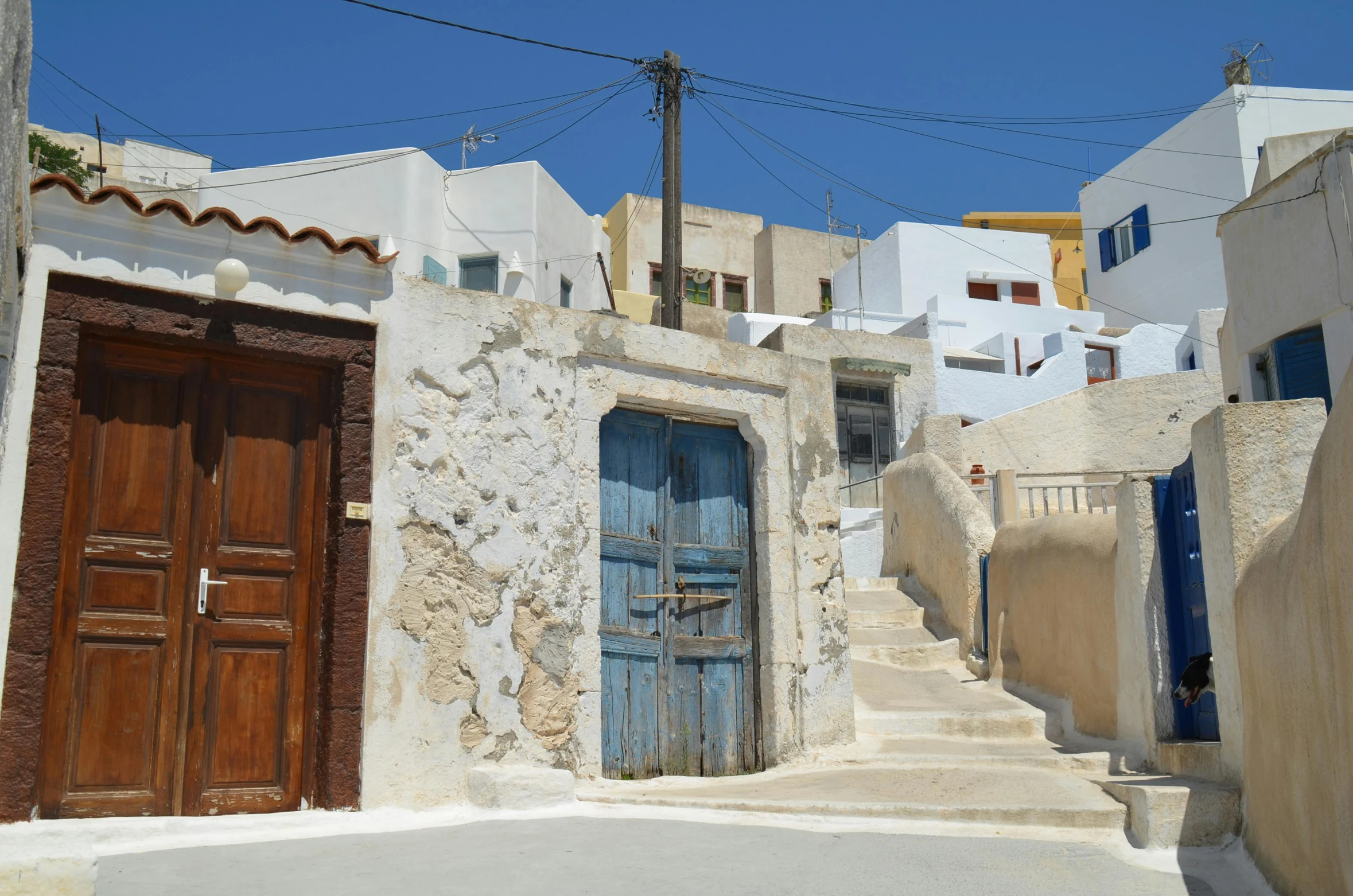 a couple of wooden doors sitting on the side of a building, whitewashed buildings, pathos, built on a steep hill, profile image