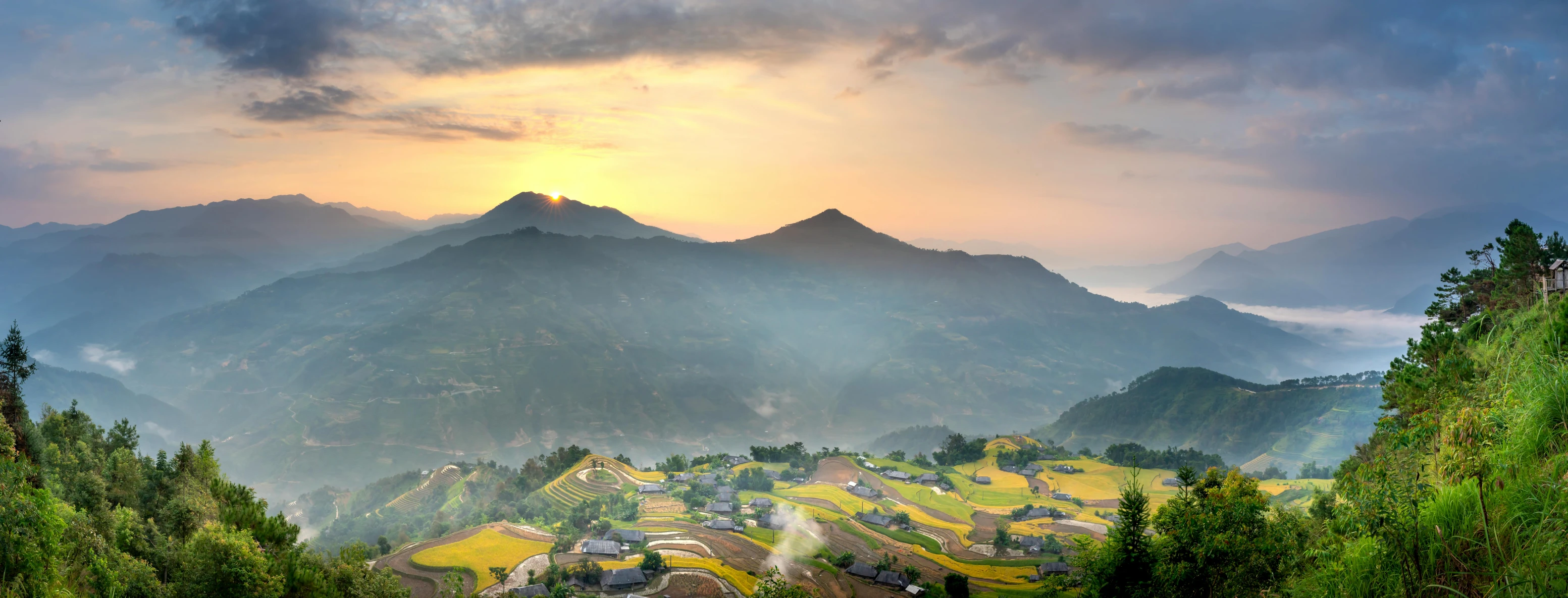 a view of a valley with mountains in the background, by Reuben Tam, pexels contest winner, patches of yellow sky, rice paddies, slide show, light coming through